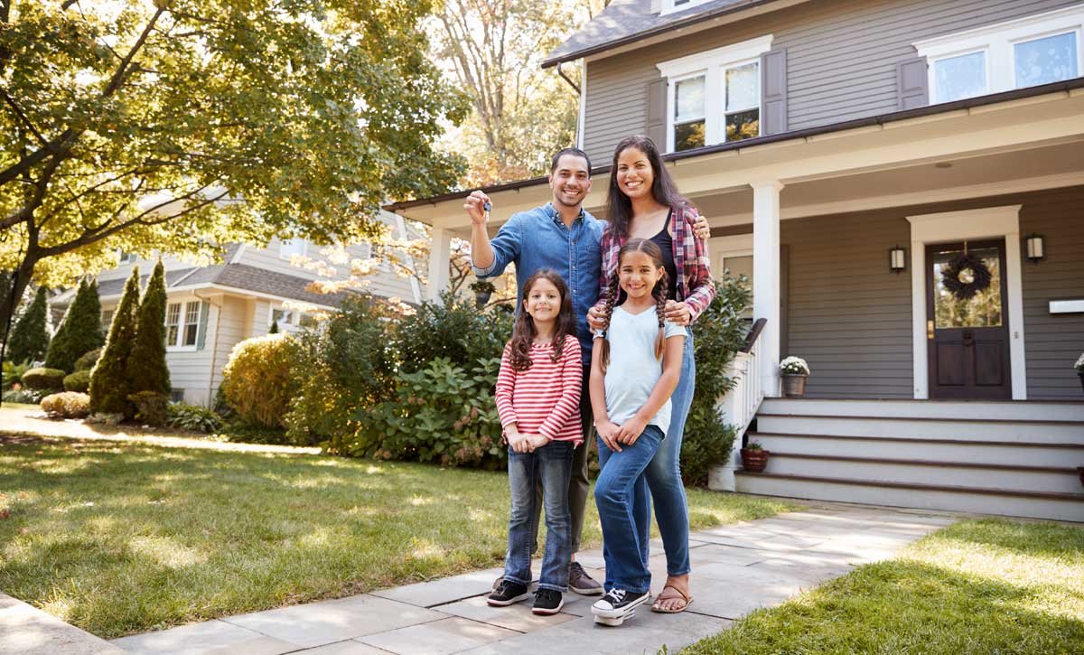 Family of four standing in front of home